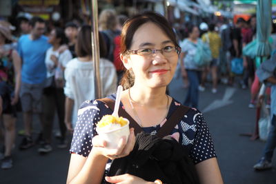 Portrait of smiling woman holding ice cream in city