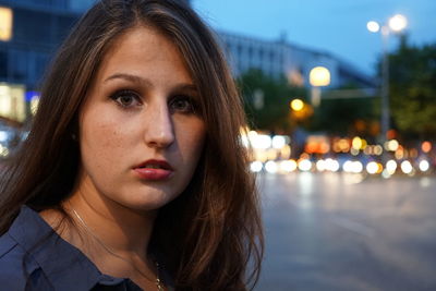 Portrait of shocked woman standing on street at dusk