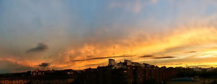 Silhouette buildings against dramatic sky during sunset