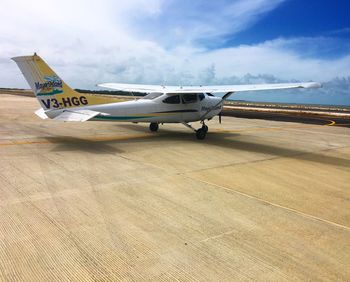 Airplane at airport runway against sky