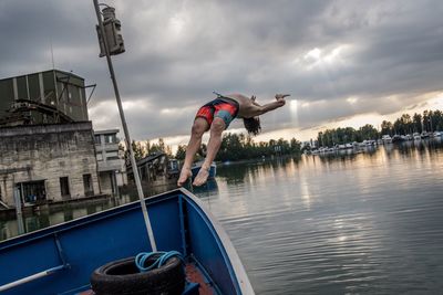 Man diving in lake against sky