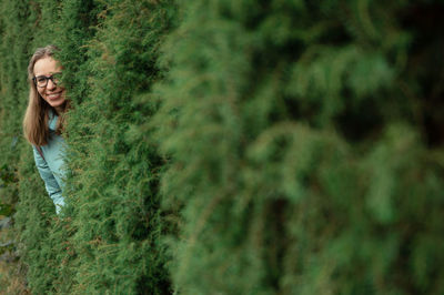 Portrait of young woman standing against trees