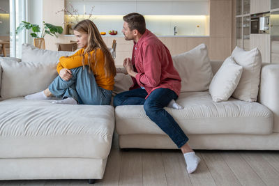 Young woman using phone while sitting on sofa at home