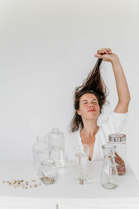 Portrait of young woman holding bottle against white background