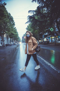 Young woman with umbrella on road in city