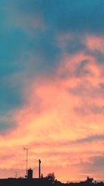 Low angle view of silhouette factory against sky during sunset