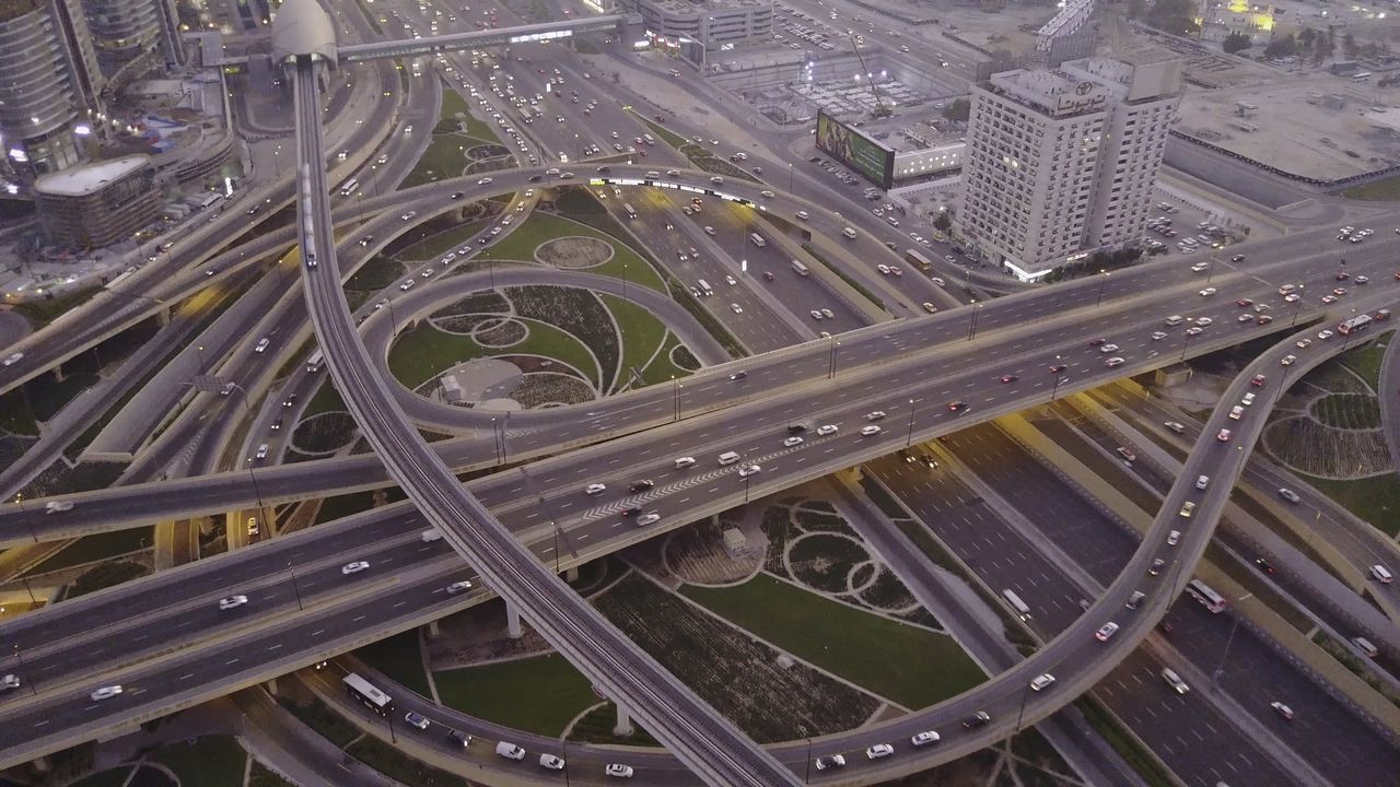 junction, city, architecture, transportation, road, built structure, high angle view, highway, metropolitan area, overpass, aerial view, building exterior, no people, street, crossroad, road intersection, multiple lane highway, cityscape, elevated road, aerial photography, traffic, track, mode of transportation, car, motor vehicle, city life, residential area, outdoors, freeway, transport, day, city street, infrastructure, land vehicle, building, nature, lane, complexity, bridge