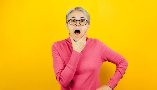 Young woman wearing hat against yellow background