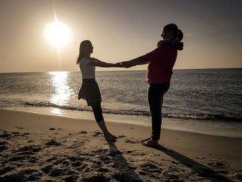 Full length of people on beach against sky during sunset