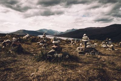 Stacks of stones on mountain against cloudy sky