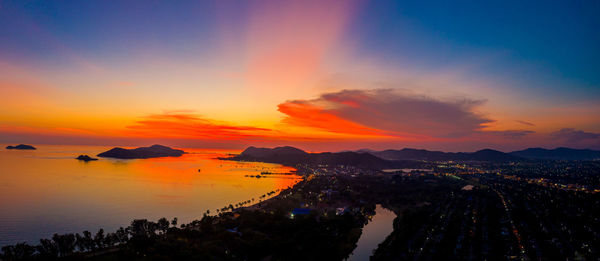 Silhouette buildings by sea against romantic sky at sunset