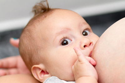 Cropped mother breastfeeding son at home