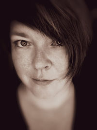 Close-up portrait of woman against black background