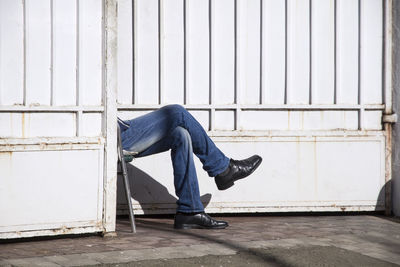 Low section of man sitting against wall