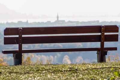 Empty bench on field against sky