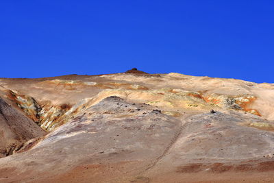 Scenic view of arid landscape against clear blue sky