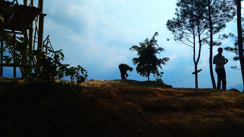 Silhouette people standing by tree against sky