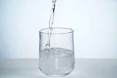 Close-up of drinking glass in water against white background