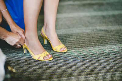 Cropped hands of woman assisting female friend wearing high heels on carpet