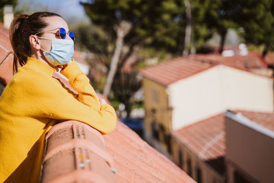 Woman wearing sunglasses standing by rooftop