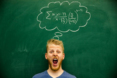 Man shouting with mathematical formula on blackboard