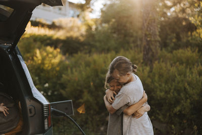 Happy brothers embracing each other while standing near car trunk