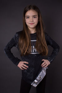 Portrait of teenage girl standing against black background