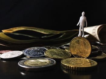 Close-up of coins and figurine against black background