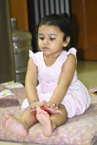 Cute girl sitting on bed at home
