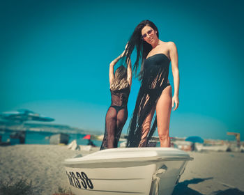 Young woman standing on beach against clear sky