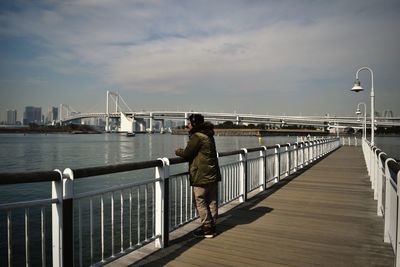 Rear view of men on bridge over sea against sky