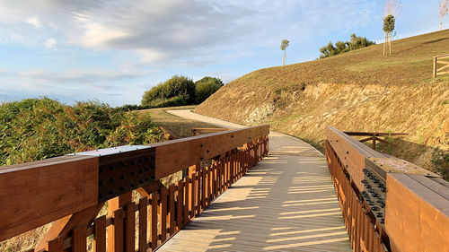 Footpath by railing against sky