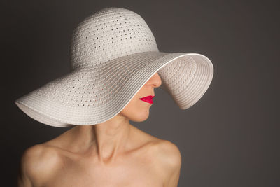 Close-up of person wearing hat against black background