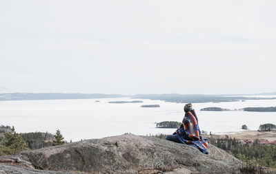 Woman sitting on a rock over looking a beautiful view of sweden