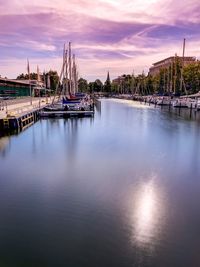 Sailboats in river against sky during sunset