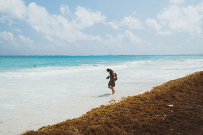 Full length of girl standing on beach against sky