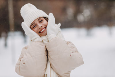 Portrait of smiling young woman standing on snow