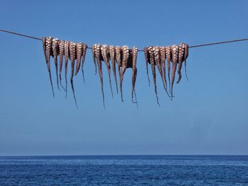 Low angle view of flags hanging against clear blue sky