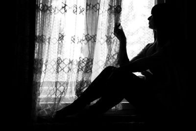 Depressed woman sitting by window at home