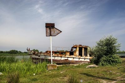 Abandoned boat on field against sky