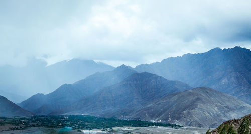 Scenic view of sea by mountains against sky