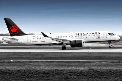 Airplane flying over airport runway against sky