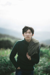 Portrait of man standing on field against sky