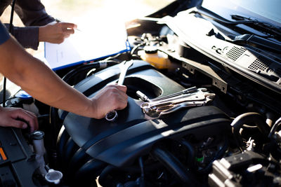 Cropped hand of mechanic repairing car engine in workshop