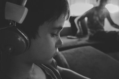 Close-up of boy wearing headphones while sitting on sofa