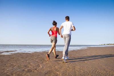 Full length of people on beach against clear sky