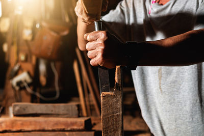 Close-up of a carpenter using a circular saw or a tool to cut wooden planks to make furniture  