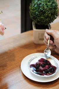 Close-up of woman holding ice cream cone on table