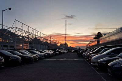 Cars parked at parking lot against sky during sunset