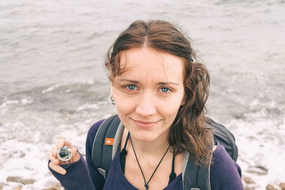 Portrait of woman holding camera at beach